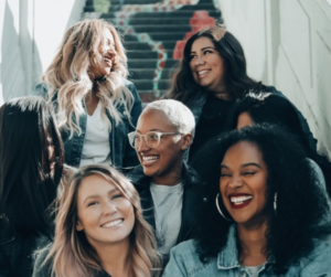 Image shows a smiling, diverse group of young women meant to be members of a book club reading books my award-winning author Patricia Raybon 