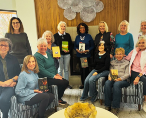 This photo shows award-winning author Patricia Raybon posing with a big smile with smiling members of the Page Turners Book Club in Denver, Colorado. Several members are holding copies of Patricia's popular novels and books including "Double the Lies," "I Told the Mountain to Move," and "My First White Friend."